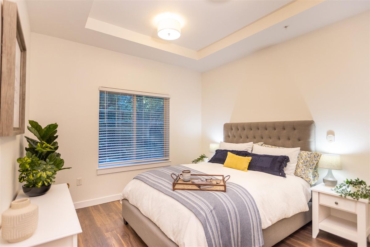 A cozy and modern bedroom featuring a neatly made bed with layered bedding and decorative pillows, complemented by a large window.