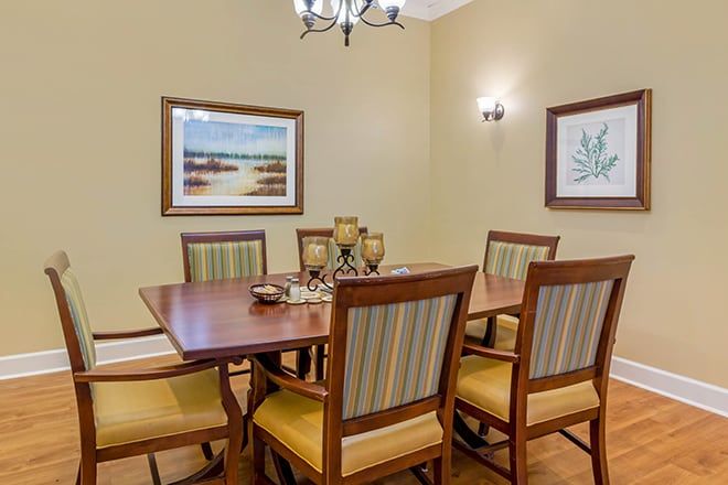 A cozy dining room with a wooden table and upholstered chairs, adorned with wall art and ambient lighting.
