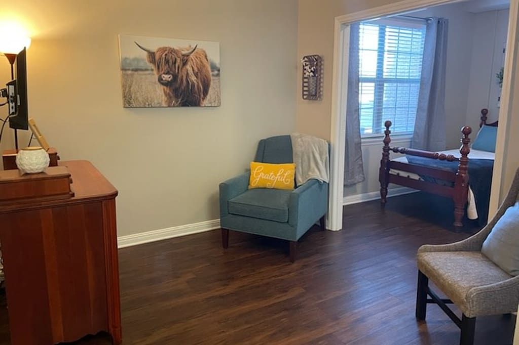 A cozy living room corner with an armchair and artwork on the wall.