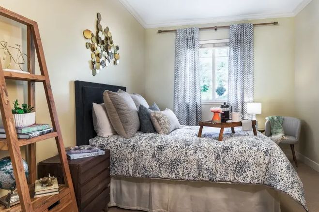 A cozy bedroom with a neatly made bed, decorated pillows, and soft lighting.