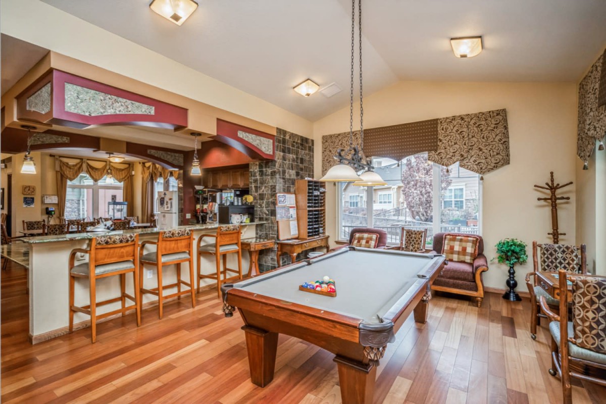 A cozy game room featuring a pool table and bar area with hardwood flooring.
