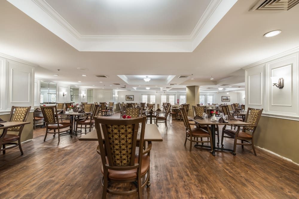 A spacious dining room with neatly arranged tables and chairs on a hardwood floor.