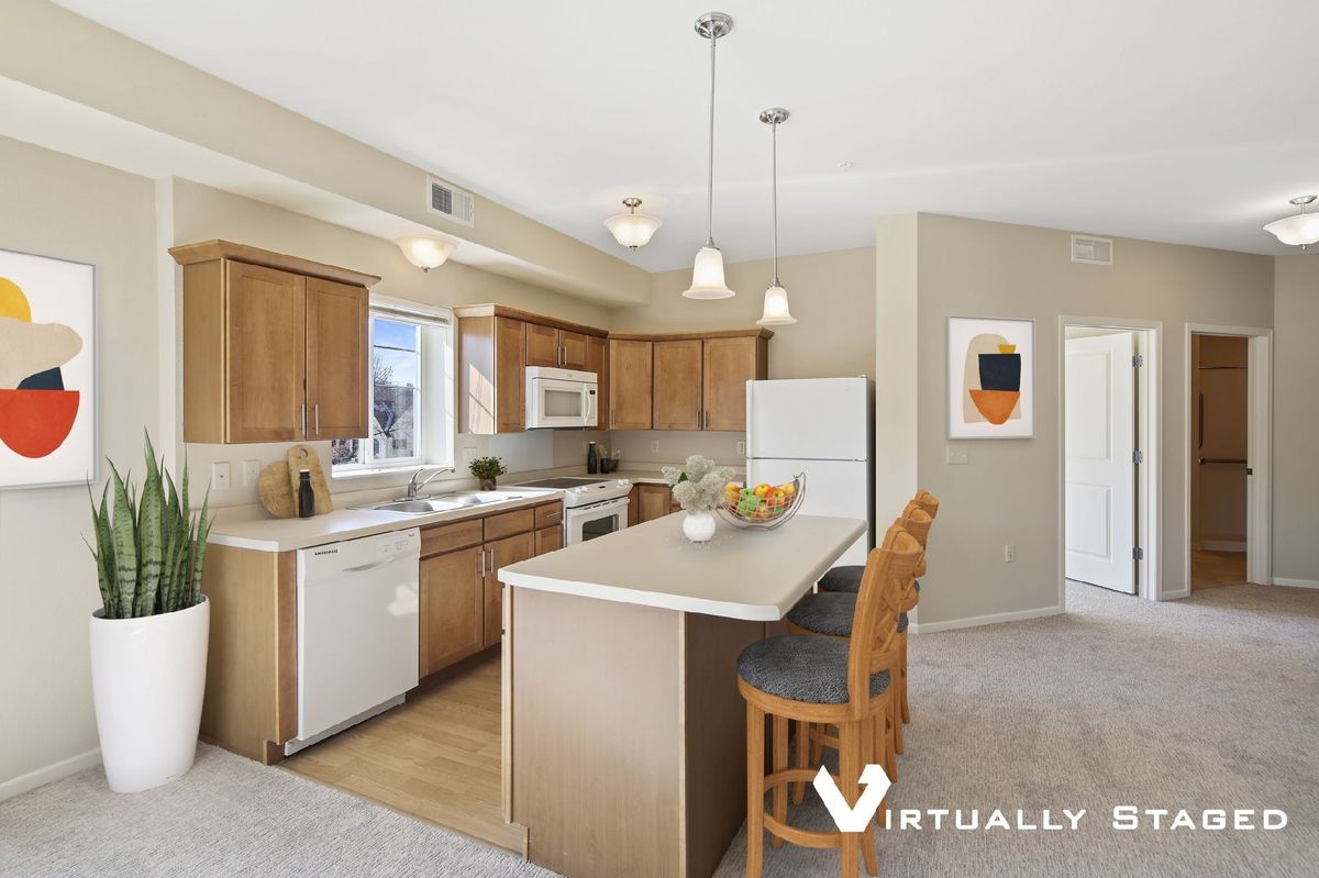 A modern kitchen with wooden cabinets, an island counter, and contemporary lighting.