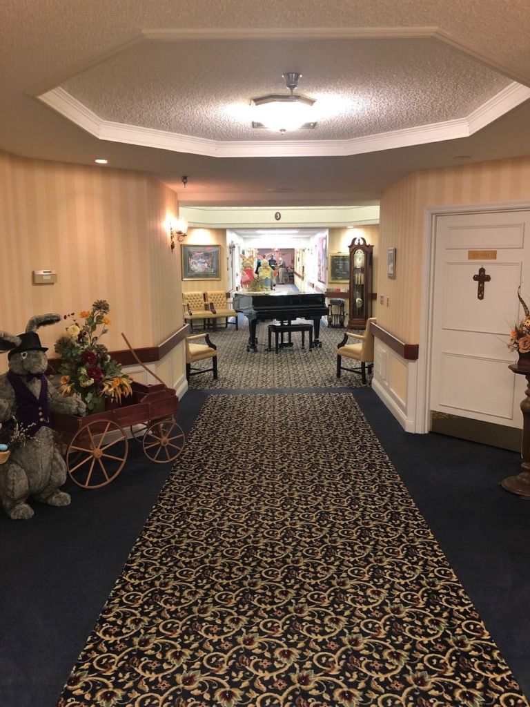 A hallway with elegant decor featuring a piano and floral arrangements.