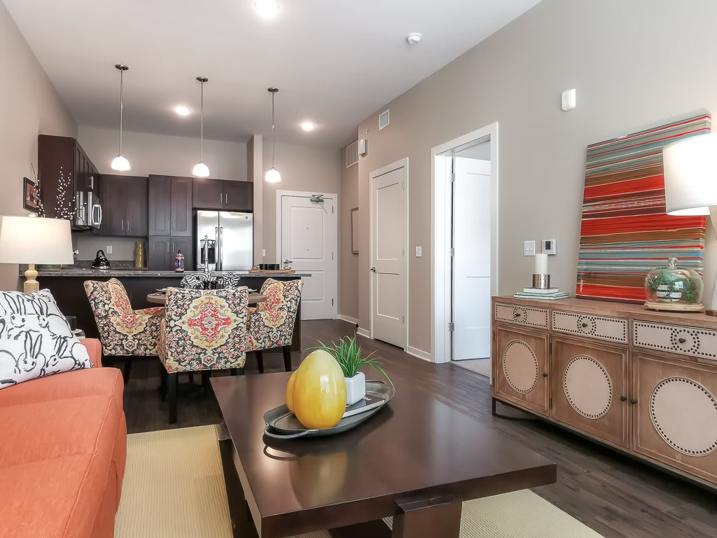 A modern open floor plan living space featuring a kitchen with dark cabinets and a cozy living area with colorful decor.