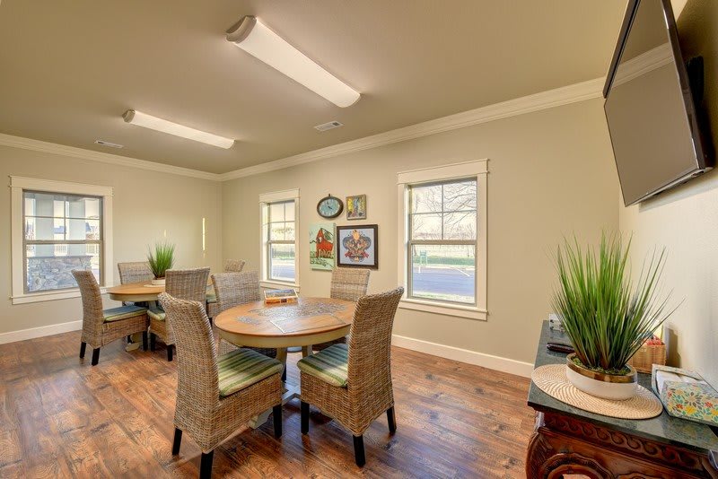 A cozy dining area featuring round tables, wicker chairs, and decorative plants under soft lighting.