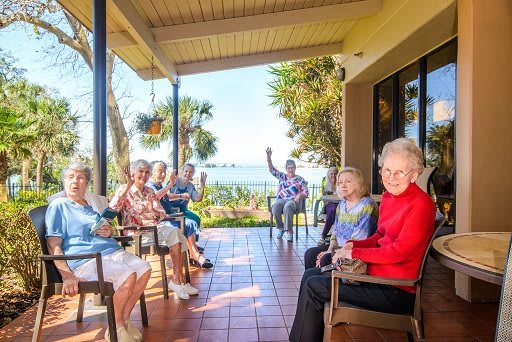 A group of seniors enjoying a sunny day on a patio with an ocean view.