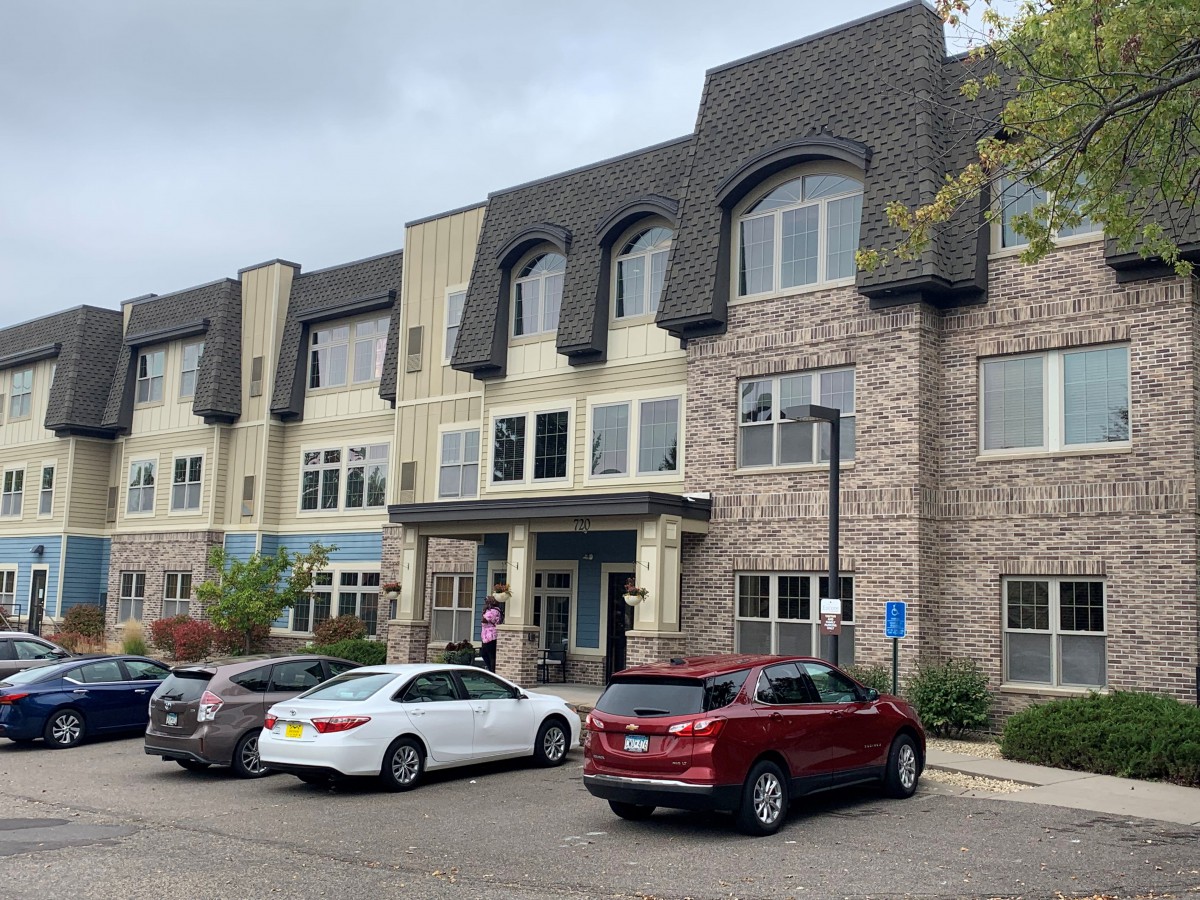 A view of a multi-story building with parked cars in front.