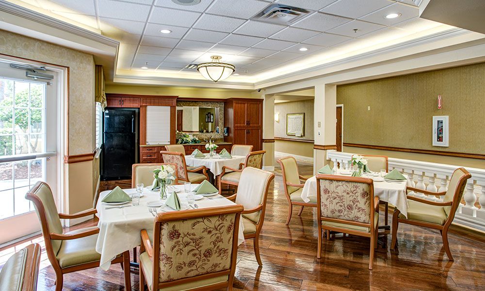 A elegantly set dining area with multiple tables and chairs, featuring warm lighting and tasteful decor.