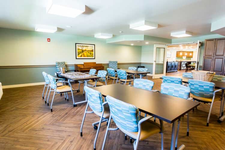 A modern conference room with tables and chairs arranged for meetings, featuring bright lighting and contemporary decor.