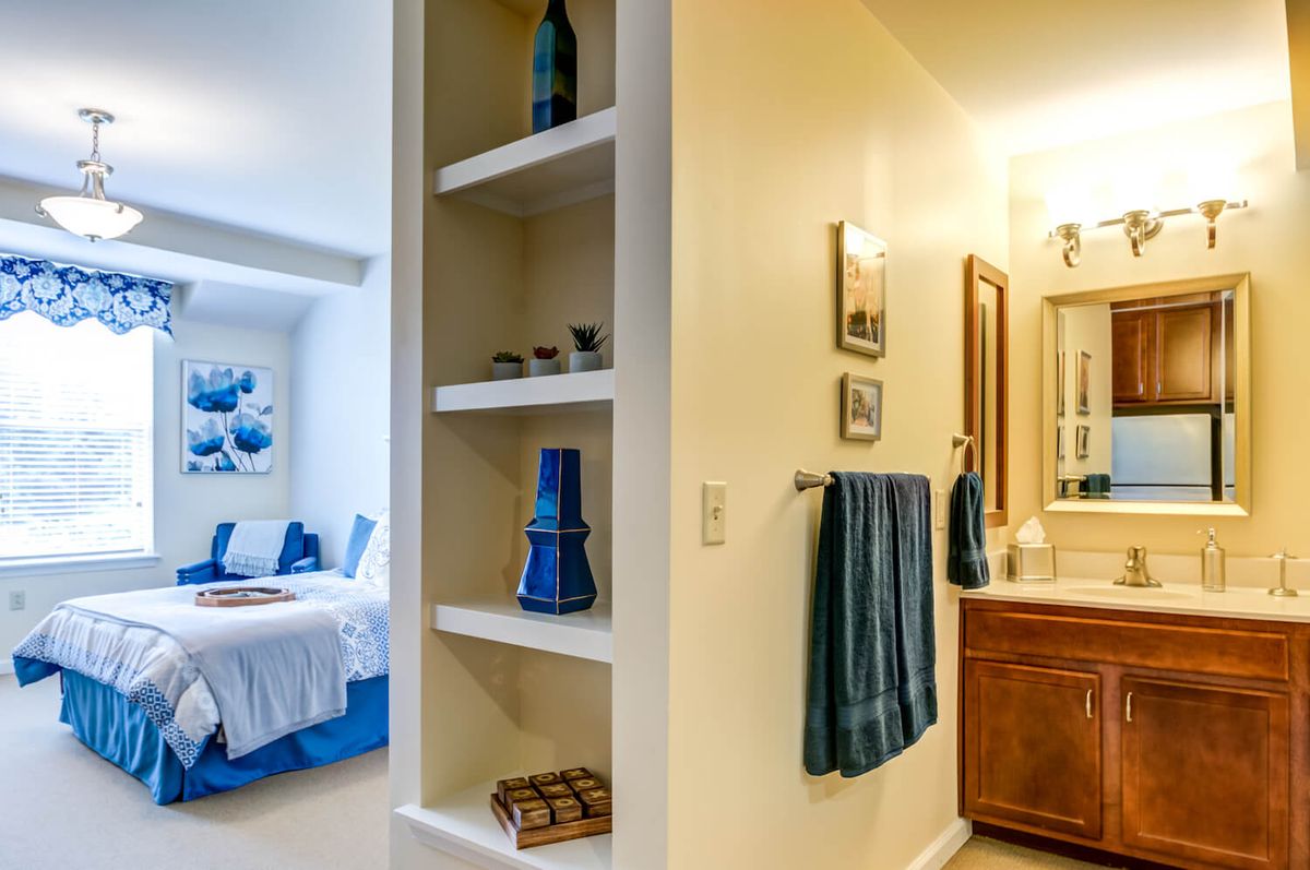 A cozy bedroom with adjacent bathroom featuring open shelves and blue accents.