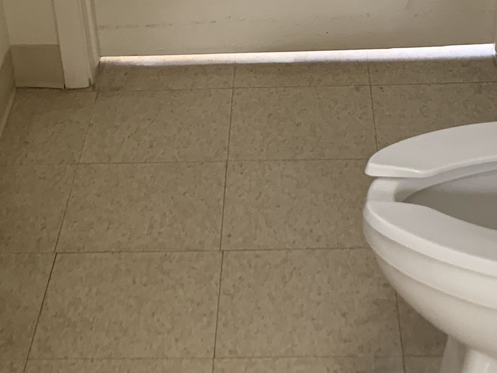 A tiled bathroom floor with a toilet in view.