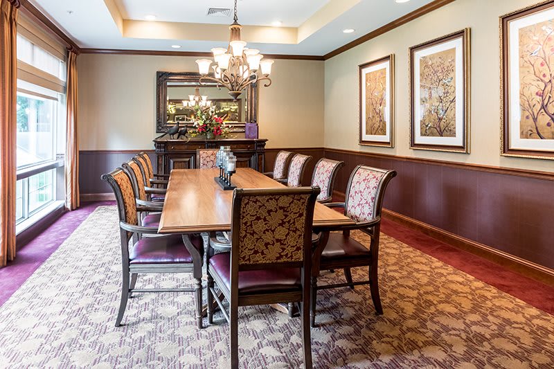 A well-decorated dining room featuring an elegant table with patterned chairs, a chandelier, and framed artwork on the walls.