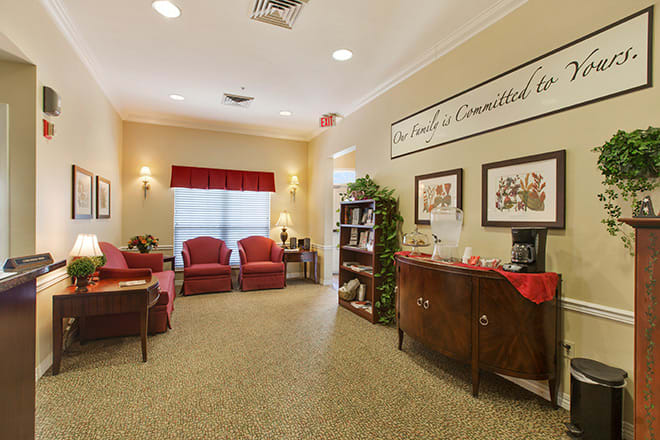 A cozy waiting room with red chairs and warm lighting.