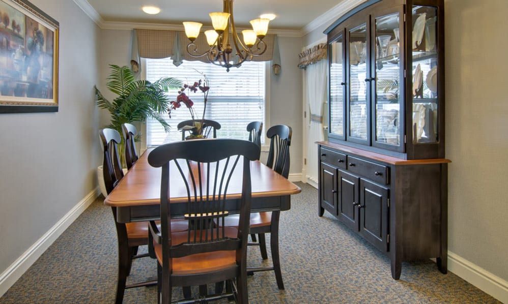 A traditional dining room with a wooden table, chairs, and a large cabinet under a chandelier.