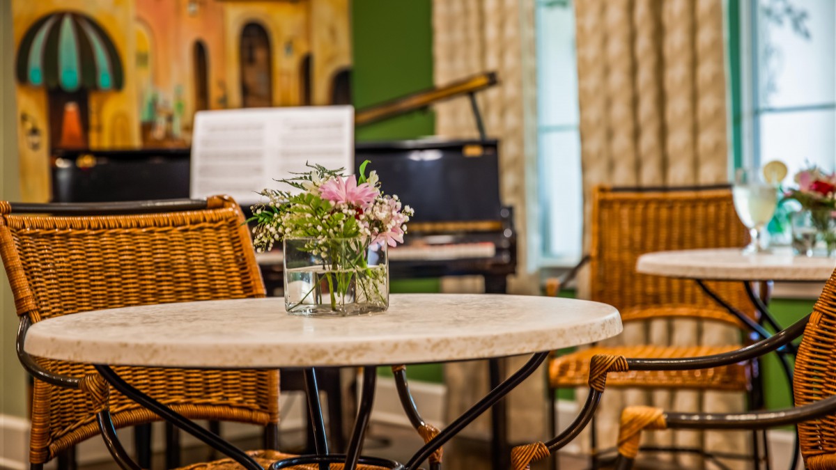 A cozy room with a table centerpiece and a piano in the background.