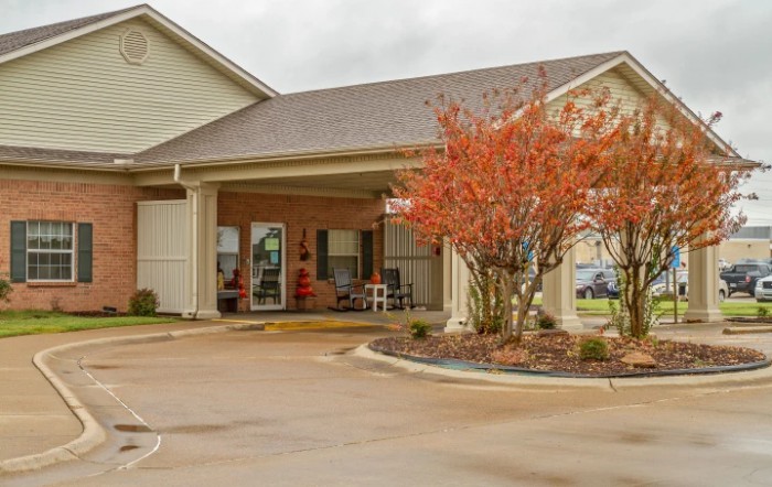 A building entrance with a landscaped garden and driveway.