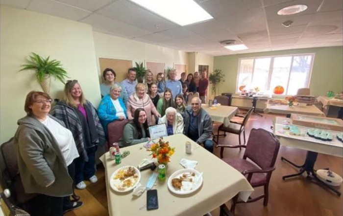 A family gathering indoors, celebrating around a table filled with food.