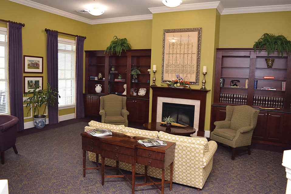 A cozy traditional living room with a fireplace, bookshelves, and comfortable seating.