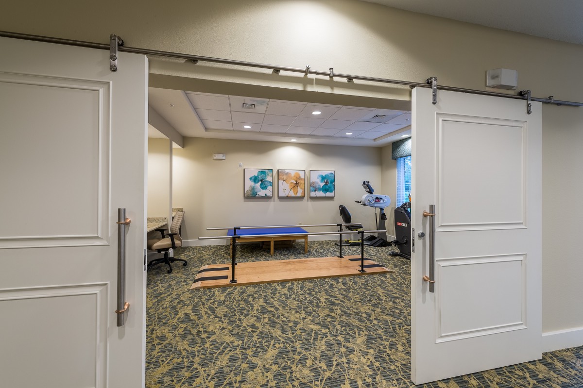 A physical therapy room equipped with exercise equipment and parallel bars.