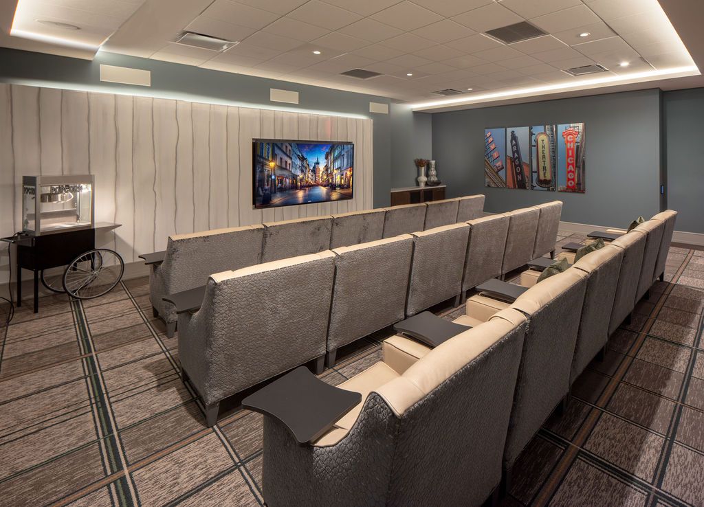 A modern home theater with comfortable seating and a large projector screen, featuring stylish artwork on the walls.