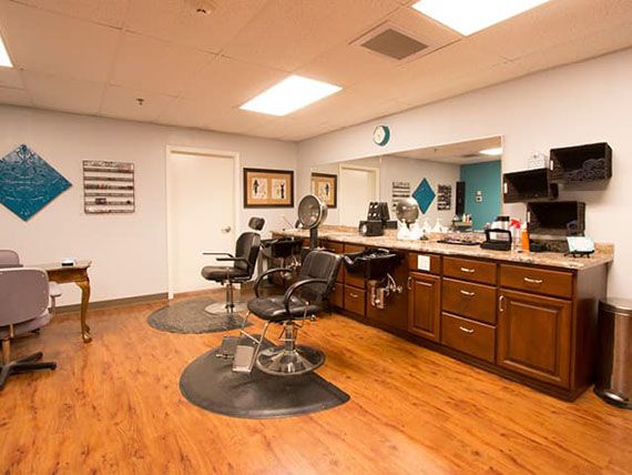 An empty barber shop with wooden floors and styling chairs.