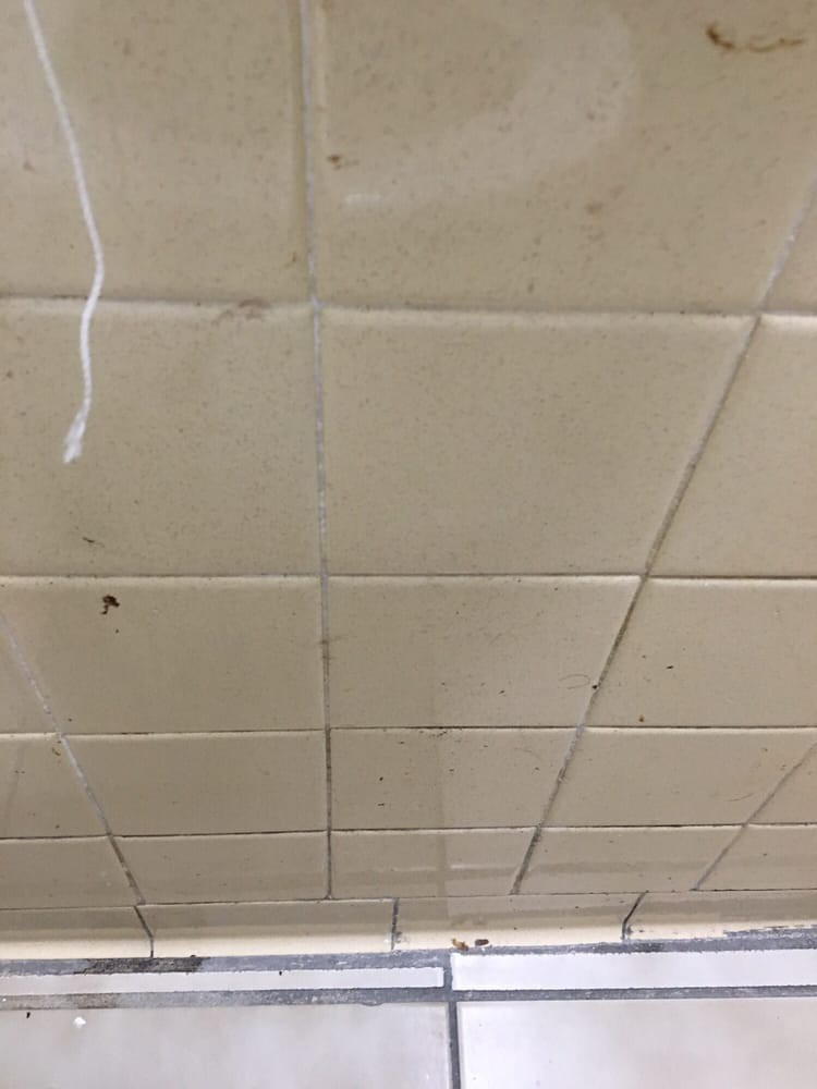 A damaged ceiling with tiles showing cracks and signs of water damage.
