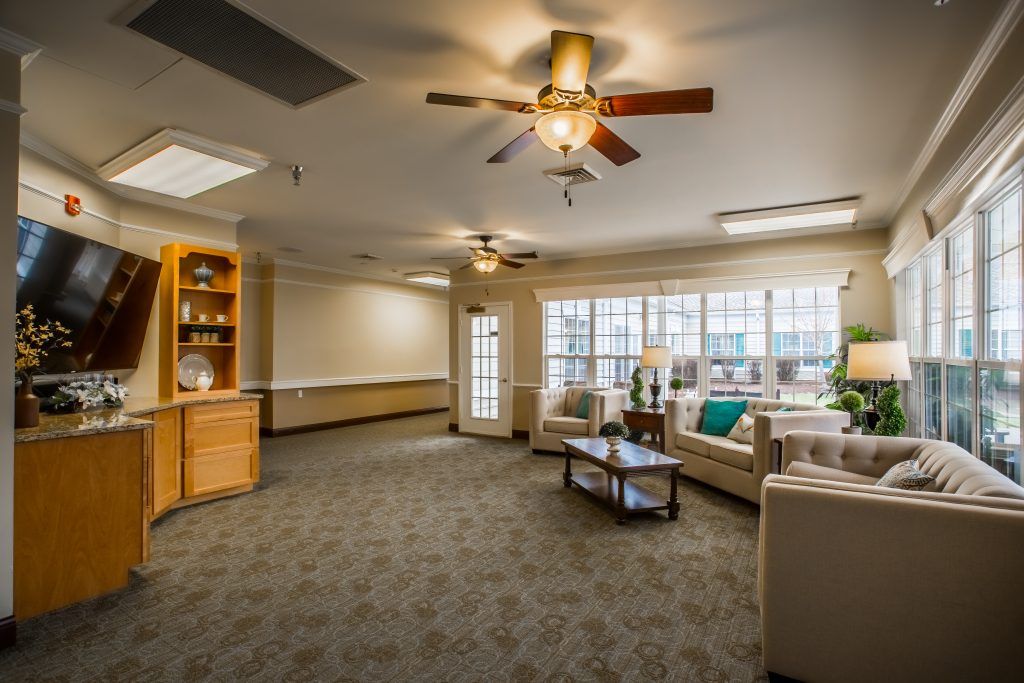 A cozy living room with comfortable seating, ceiling fans, and a large window letting in natural light.
