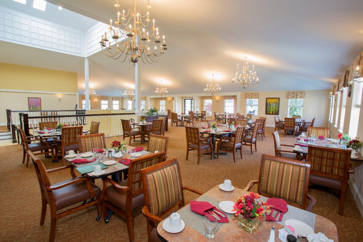 A spacious dining area with elegant chandeliers and neatly arranged tables and chairs.