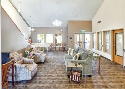 A spacious lobby area with comfortable seating and a chandelier, flooded with natural light.