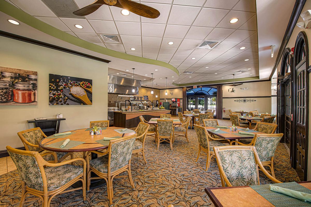An empty restaurant dining area with neatly arranged tables and chairs under soft indoor lighting.