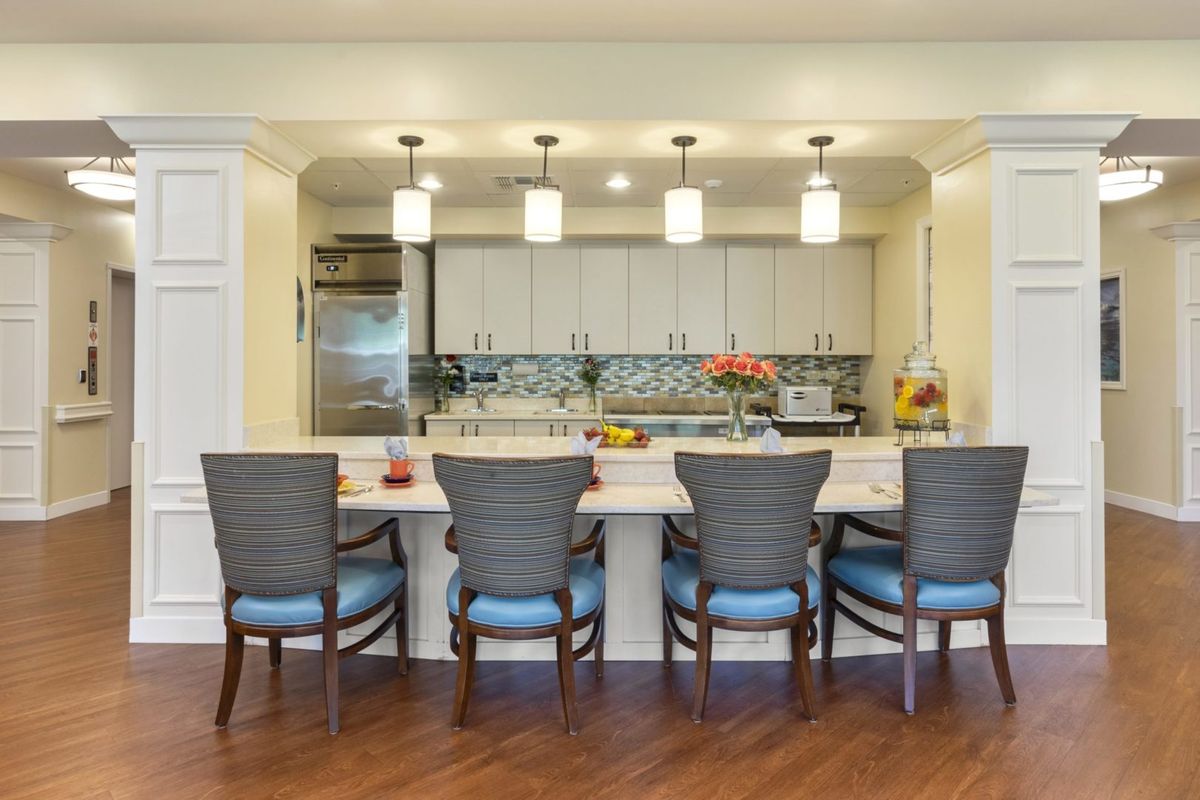 A modern kitchen with a countertop and bar stools, featuring pendant lighting and stylish decor.