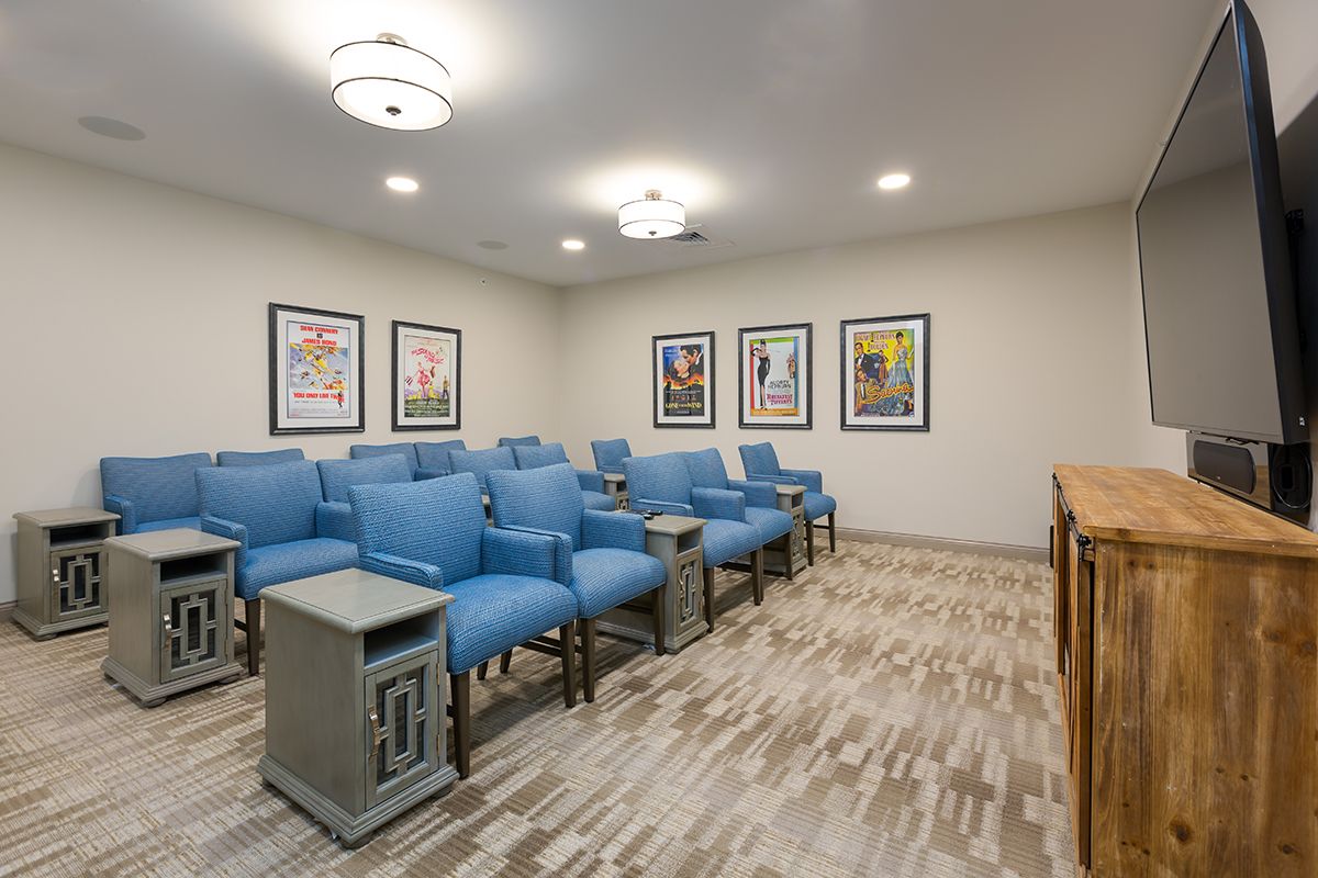 A cozy home theater room with blue chairs and movie posters on the walls.
