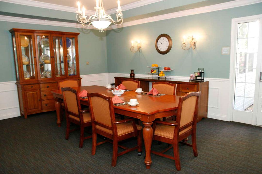 A well-arranged dining room with a wooden table, chairs, and a chandelier.