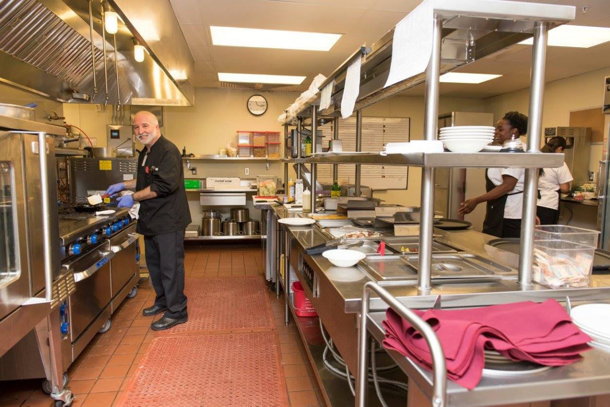 Chefs working in a busy commercial kitchen preparing food.
