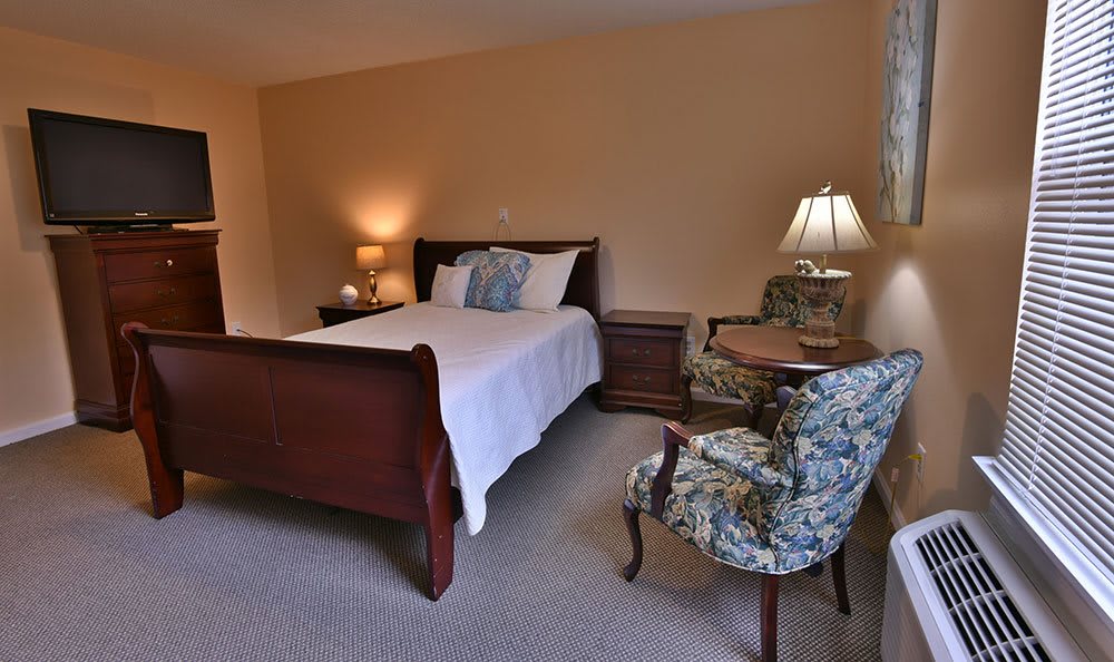 A cozy bedroom with a wooden bed, nightstands, and a floral armchair.