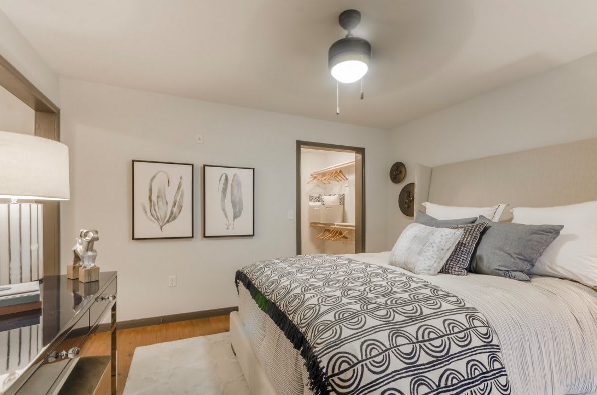A modern bedroom with stylish decor, featuring patterned bedding and abstract artwork on the walls.