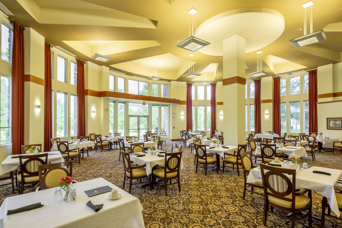 An elegant and spacious dining room with tables and chairs, featuring large windows and stylish lighting.