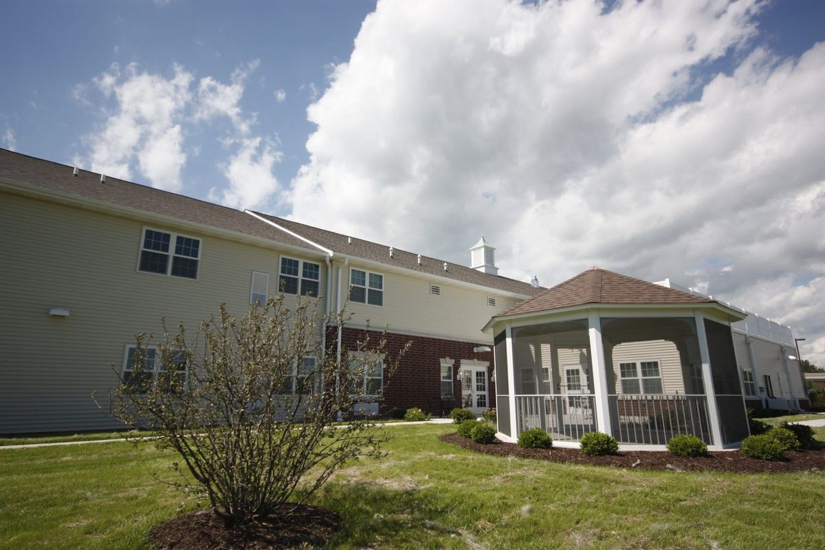 A residential building with a gazebo and lawn under a cloudy sky.