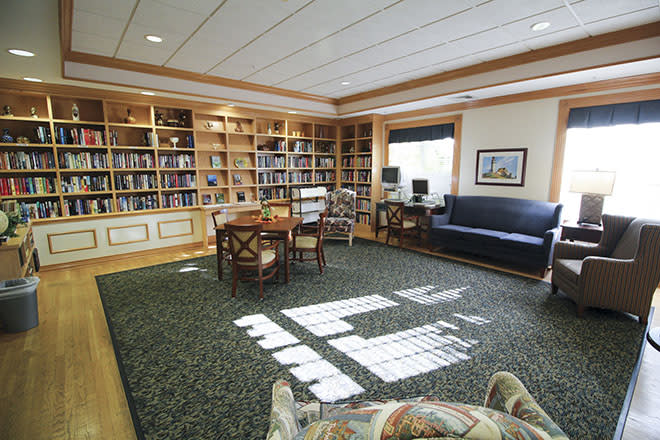 A cozy library with bookshelves, a reading table, and comfortable seating.