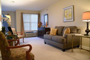 A cozy living room with a sofa, chairs, and natural light from the window.