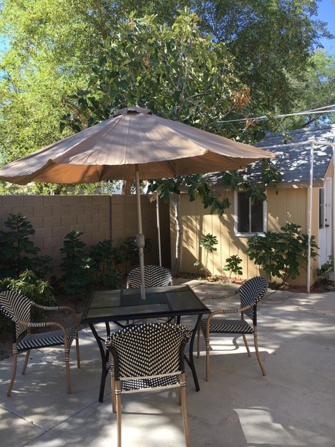 A cozy backyard patio with a table and chairs under a large umbrella.