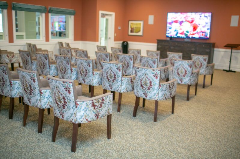 A room set up with rows of patterned chairs facing a television screen.