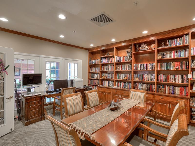 A cozy library office with a conference table and bookshelves filled with books.