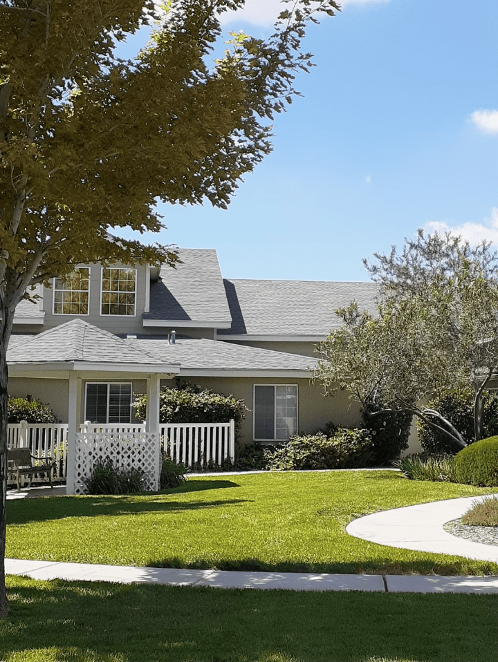 A suburban house with a well-maintained lawn, a gazebo, and surrounding trees.