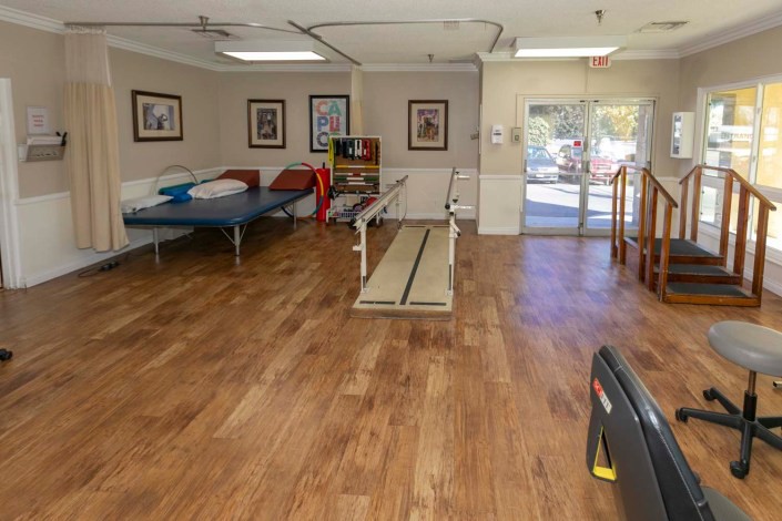 A spacious rehabilitation room equipped with therapy beds and exercise equipment.