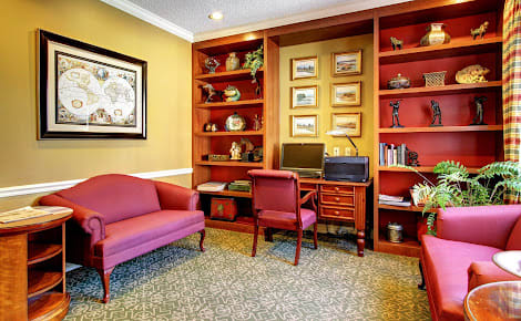 A cozy home office with wooden bookshelves, a desk with a computer, and comfortable seating.