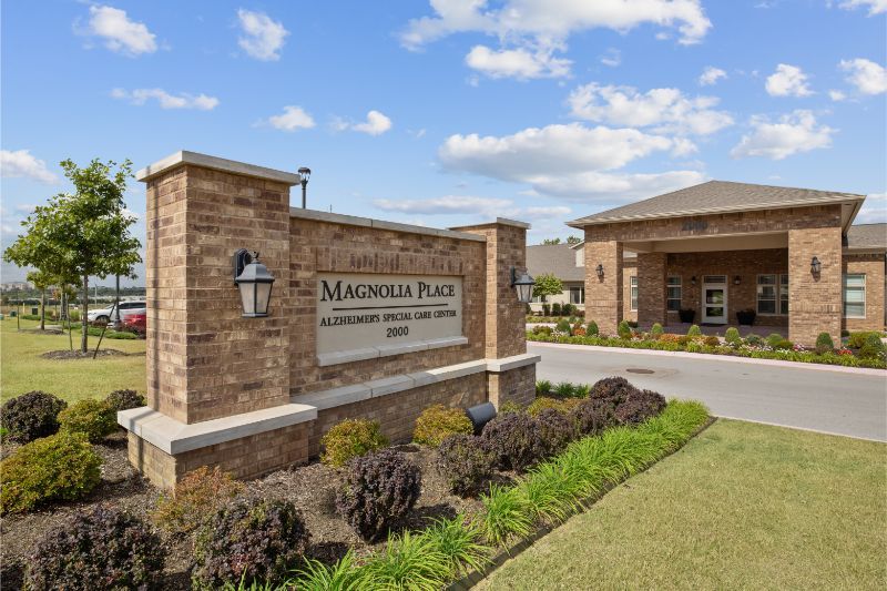 Entrance to Magnolia Place apartment complex with landscaped surroundings.