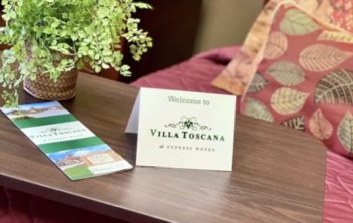 A welcome card from Villa Toscana placed on a table, accompanied by a brochure and a potted plant.