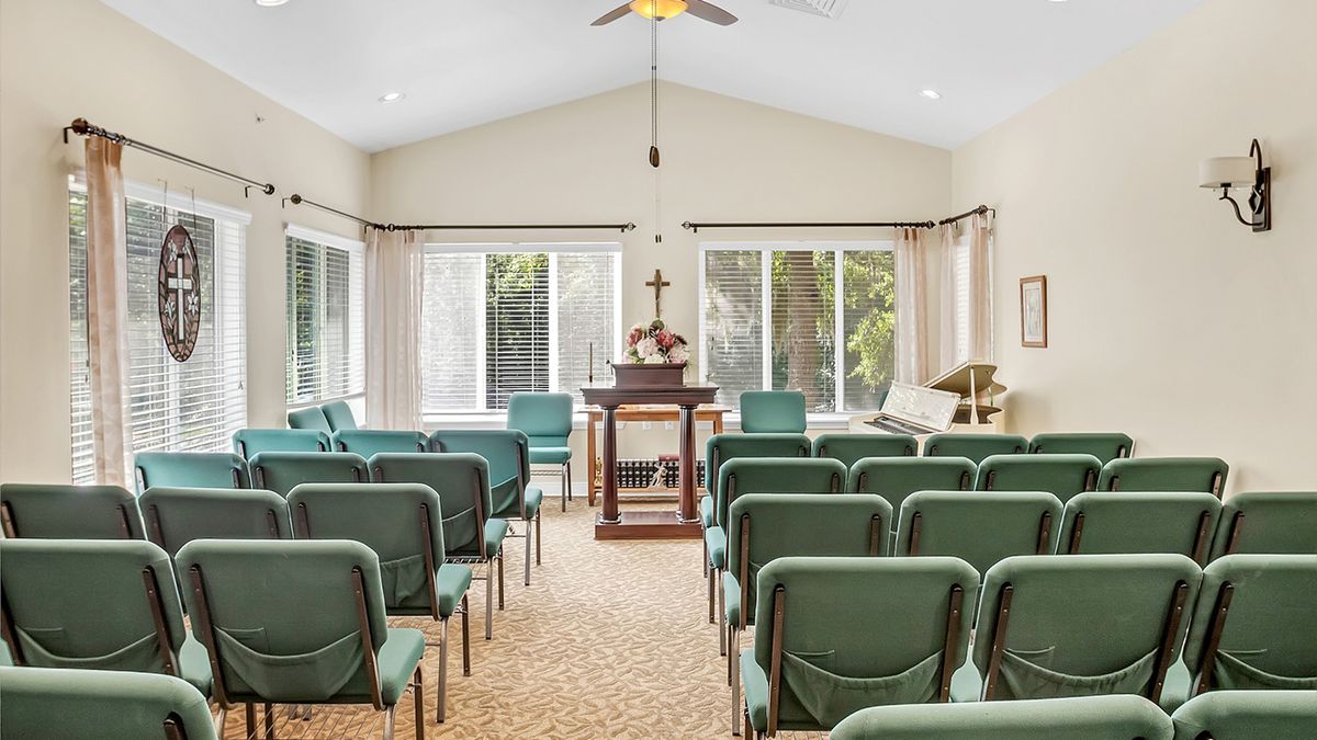 Interior view of a small chapel with rows of chairs and a pulpit at the front.
